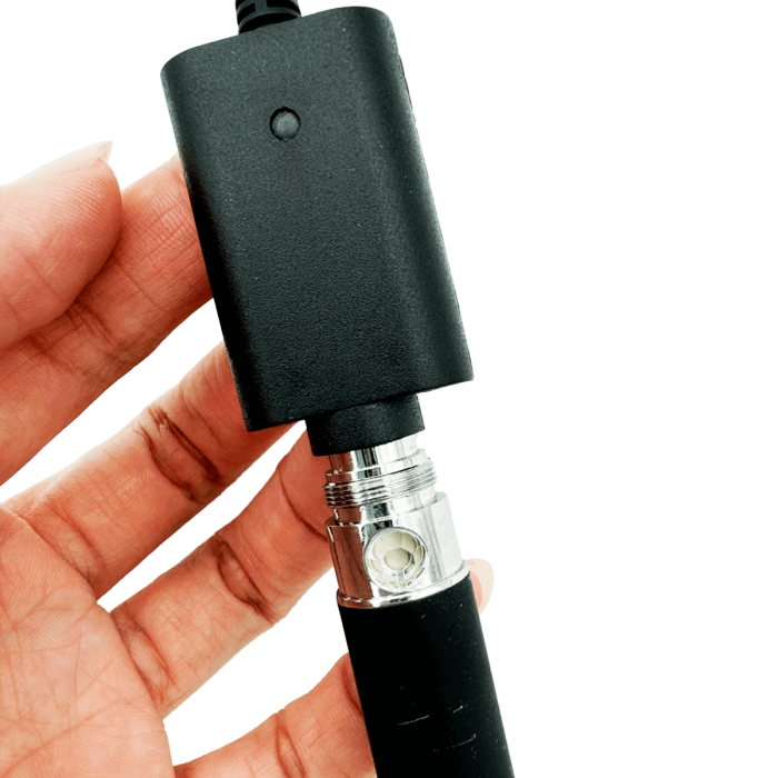 Batería de vapeador conectada a cargador USB con enchufe a pared.