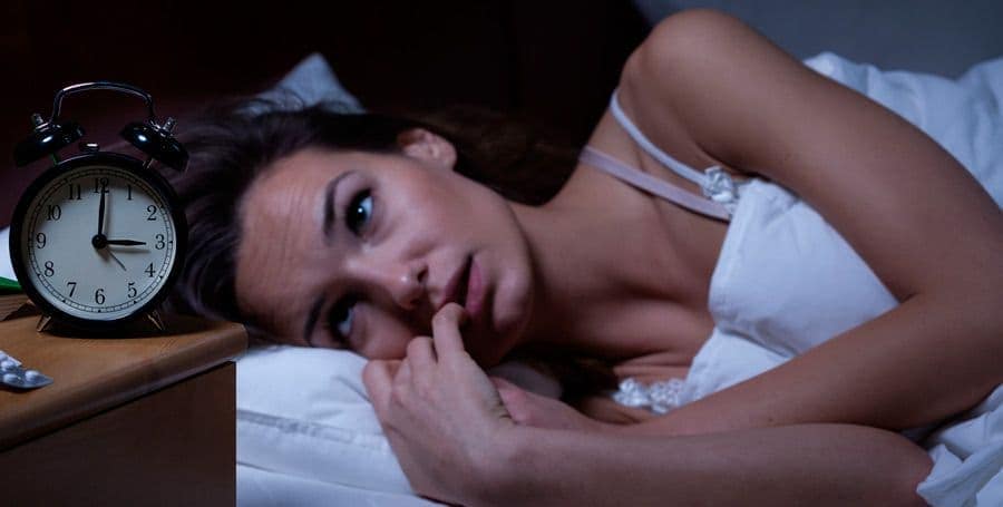 Girl wakes up at 3 AM looking at the clock with trouble sleeping and falling asleep